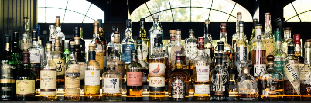 Assorted liquor bottles in a bar. Plastic-related contaminants in liquor products were even found in glass packaging.